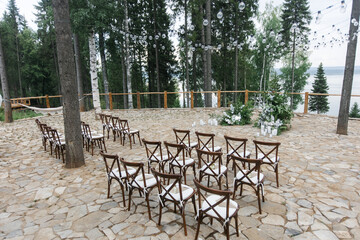 brown wooden chairs with cross-backs. Wedding decoration in nature, against the backdrop of the river and pine trees. natural wedding decor in a rustic style. holiday concept.
