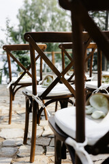 brown wooden chairs with crisscross back. White pillows on chairs and envelopes with white rose petals. against the backdrop of nature on a stone floor. holiday concept.