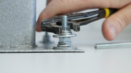 Constructor Screwing a Nut onto a Metal Screw and Tightly Secure a Part of a Mechanical Assembly