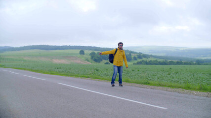 Obraz premium man hitchhiking in the countryside, on an empty road without cars