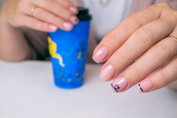 The hands of a young woman with a soft nude gel polish and design. Ideas for manicure.