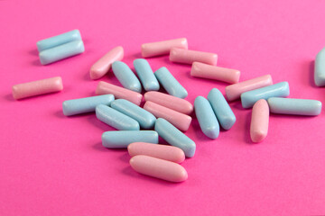 Bright blue and pink colorful candies scattered on bright pink background