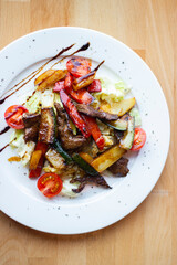 Delicious and healthy salad with grilled vegetables on a white plate in a restaurant