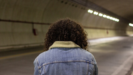 Persona con afro de espaldas dentro de t&uacute;nel