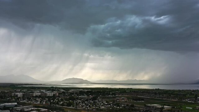 Flying towards summer rainstorm in Utah Valley as it rain curtain drapes over the landscape.