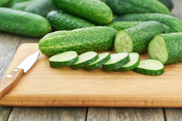 Whole and sliced cucumbers on a cutting board, rustic style.