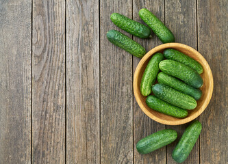 fresh cucumbers in a wooden bowl on a wooden table with copy space for text.