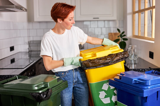Activist taking care of environment during sorting waste to proper recycling bin. Woman with recycle bin. Throwing rubbish garbage for recycling. Portrait of pleasant redhead woman in casual wear