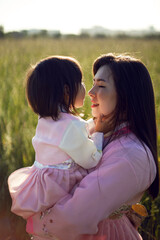 koreans family mother and daughter in pink dresses sitting in the long grass