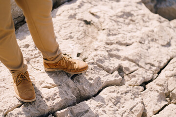Male legs in brown brogues on the rock. Close-up