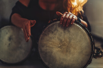 beautiful young girl playing on djembe.