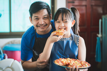 Daughter and father make pizza together happily in the kitchen. Family cooking concept