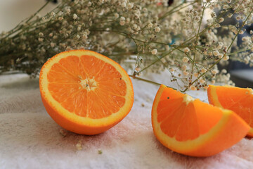 oranges on a white bed and a bouquet of flowers. fresh oranges. fruits lie on a white bed.orange fruit on a table