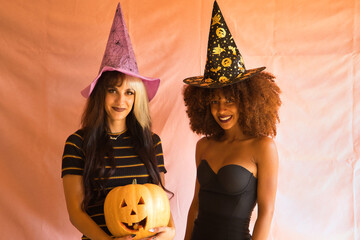 Portrait of young Hispanic and Latina women smiling and wearing a witch hat with a Halloween...