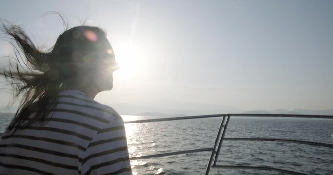 Back View Of Man With Long Hair Rippling Sitting On Fast Moving Yacht Bow At Sunset, Shaky Hand Handled Footage.