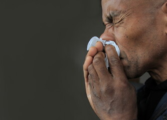 man blowing his nose after catching a cold with grey background stock photo 