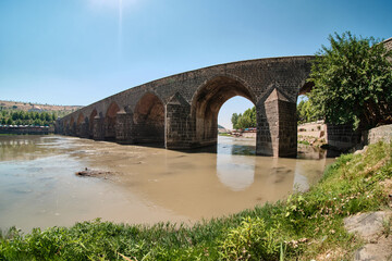 Fototapeta na wymiar The Dicle Bridge over the river Tigris in Diyarbakir, southeastern Turkey. Called also On Gozlu Kopru, literally Ten Arches Bridge. Ultra wide angle view