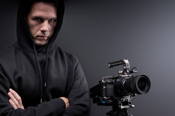 maniac filming victim on camera, watching, looking at camera, isolated on black studio background. Portrait of guy in black wear looking frightening. Copy space. People kidnapping, pedophile concept