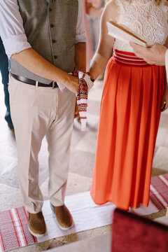 Bride And Groom Stand On An Embroidered Towel In Front Of The Priest With A Towel Tied On Their Hands