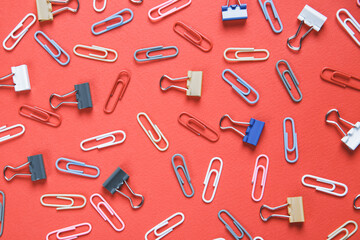 A lot of colorful paper clips lie on an red background.