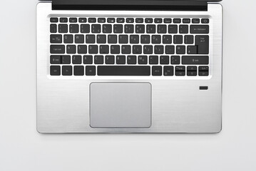 Fototapeta na wymiar Keyboard of a modern compact laptop with English layout and touchpad. Minimal workspace with portable computer laptop keyboard for online working and writing text.