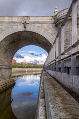 One of the arches of the Toledo bridge seen in Madrid Rio park one day with rain clouds hovering in the sky