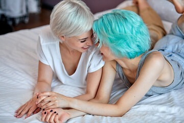 Obraz na płótnie Canvas Positive Optimistic Loving Same Sex Female Couple Have Rest On Bed, Laughing, Having Fun, Enjoying Spare Time Together, Talk And Smile, Hugging, In Love. People Lifestyle, LGBT, Tolerance Concept