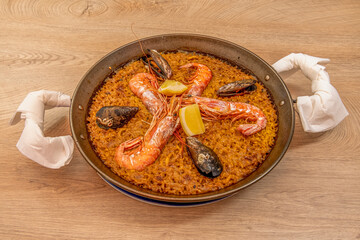 Great Valencian seafood paella popular in the Spanish summer served in a paella pan with large and appetizing prawns, fresh lemon slices and super delicious Galician mussels