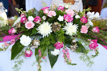 Large floral arrangement on table with greenery, pink, white and golden flowers