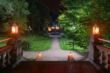Park w mieście Iłowa w Polsce w nocnej scenerii. Ciemności rozświetlają lampiony ustawione na kamiennych schodach.
