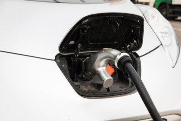 The electric vehicle at the charging station is connected to the power supply. Electric vehicle...