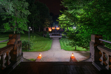 Park w mieście Iłowa w Polsce w nocnej scenerii. Ciemności rozświetlają lampiony ustawione na kamiennych schodach. - obrazy, fototapety, plakaty