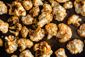 Fototapeta na wymiar Raw Cauliflower Florets Tossed in a Curry Spice Mixture: Raw cauliflower florets covered in spices on a sheet pan