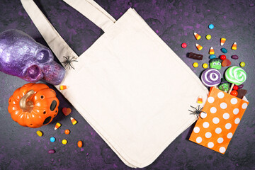 Halloween theme tote bag mockup flatlay on textured purple background with purple and orange skull,...