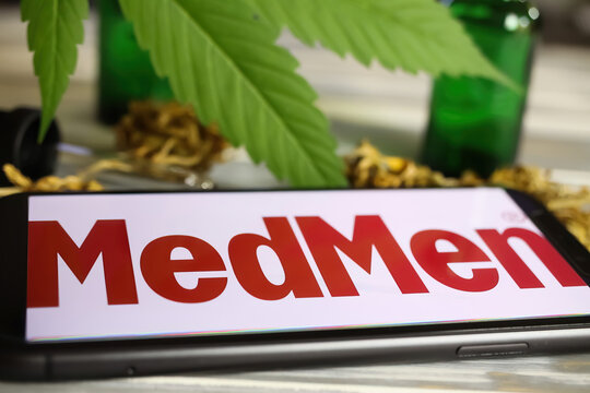 Viersen, Germany - January 9. 2021: Closeup of mobile phone screen with logo lettering of cannabinoid company medmen group, marijuana leaf background (selective fous on left lower part of letter M)