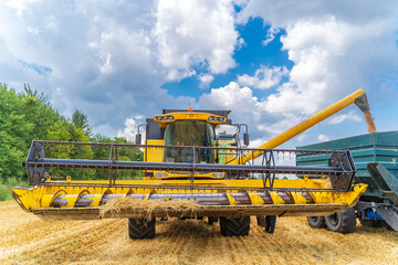Large view on yellow combine. Special technic in the field working during the summer day. Modern machinery in gold wheat concept