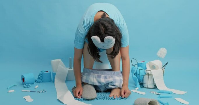Sleepy brunette woman leans to feet poses on toilet bowl reveals herself after awakening dressed in nightwear sleepmask spends long time in restroom. People sanitary and daily routines concept