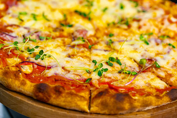 Cropped view of the delicious pizza served on wooden plate. Appetite pizza at the restaurant. Stock photo