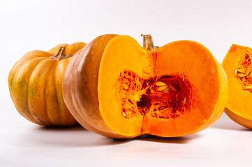Whole fresh orange big pumpkin and slice of pumpkin on white background, closeup. Organic...
