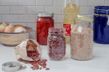 Red beans, tomatoes and grains in jars on a kitchen counter