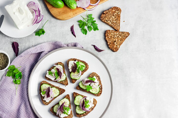 Canapes with toasted bread with sunflower and flax seeds, feta cheese, cucumber and onion