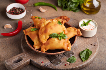 Empanada pies with minced beef meat. Freshly baked small pies served with basil leafs and sauce.