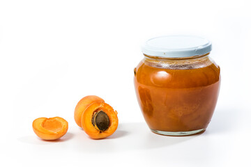 Apricot jam in a jar with apricots whole and in half over white background.