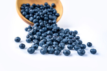 Fresh blueberries spilled from wooden bowl on blue wooden table. Healthy and dietary food concept. Blueberry is an antioxidant