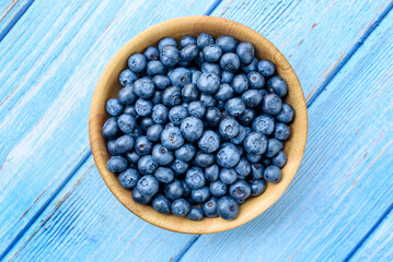 Fresh blueberries in a wooden bowl on an old blue wooden table. Healthy and dietary food concept. Blueberry is an antioxidant. Top View