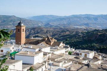 Fototapeta na wymiar views of the rooftops and tower of the church of Laroles with the Alpujarra mountains in the background