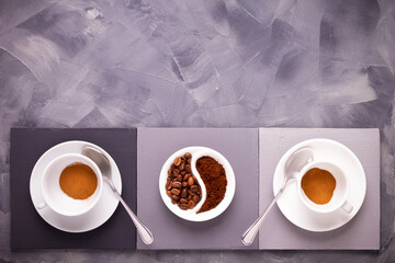 Cup of coffee on table. Coffee beans in saucer and cup on abstract painted background texture