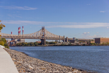 A picture of Ed Koch Queensboro Bridge in New York City, USA. In the picture one can see the East River, the Roosevelt island, Brooklyn and Domino Sugar Refinery and park