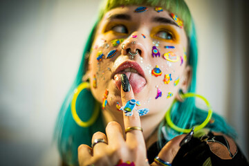 Closeup fashion portrait young pretty beautiful girl with green and blue hair. Beautiful fashion girl with luxury professional makeup and funny emoji stickers glued on the face. Young woman - obrazy, fototapety, plakaty