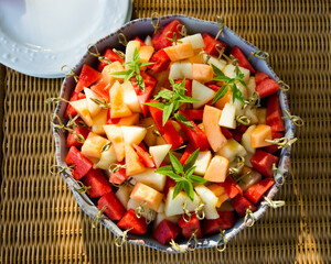 Large dish of fresh cut fruit, melon, watermelon, on bamboo sticks.